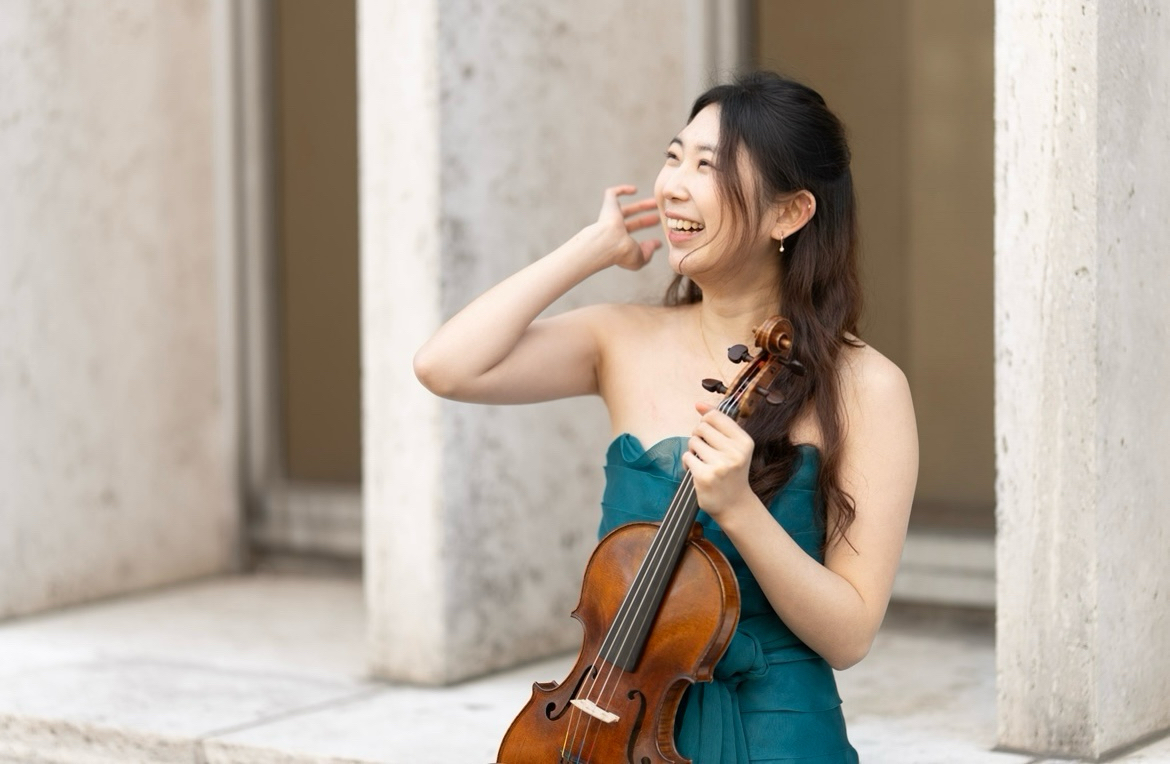Nicole Yun laughing and holding her violin between concrete columns